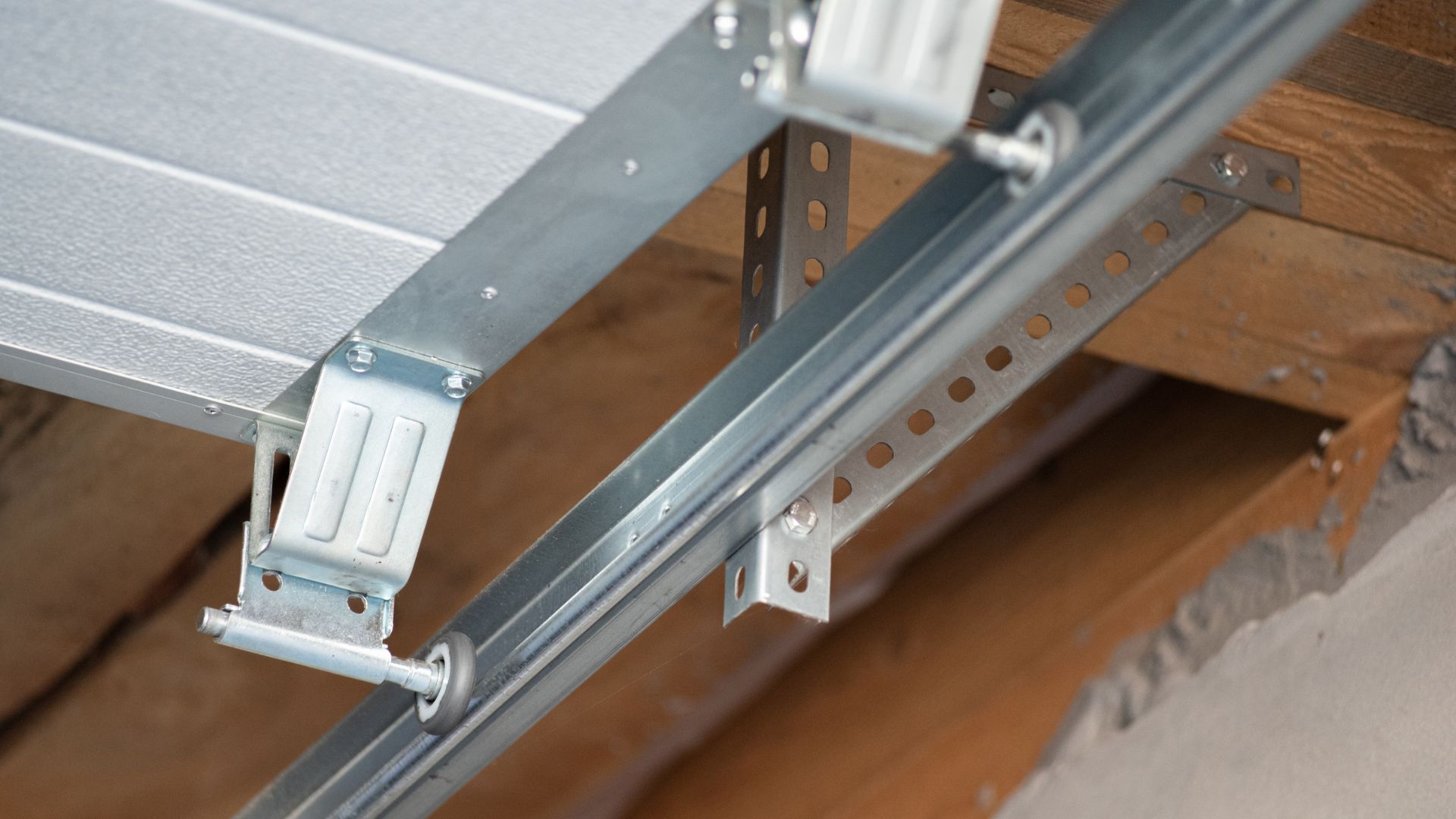 Metal garage door track and mounting bracket on wooden beam