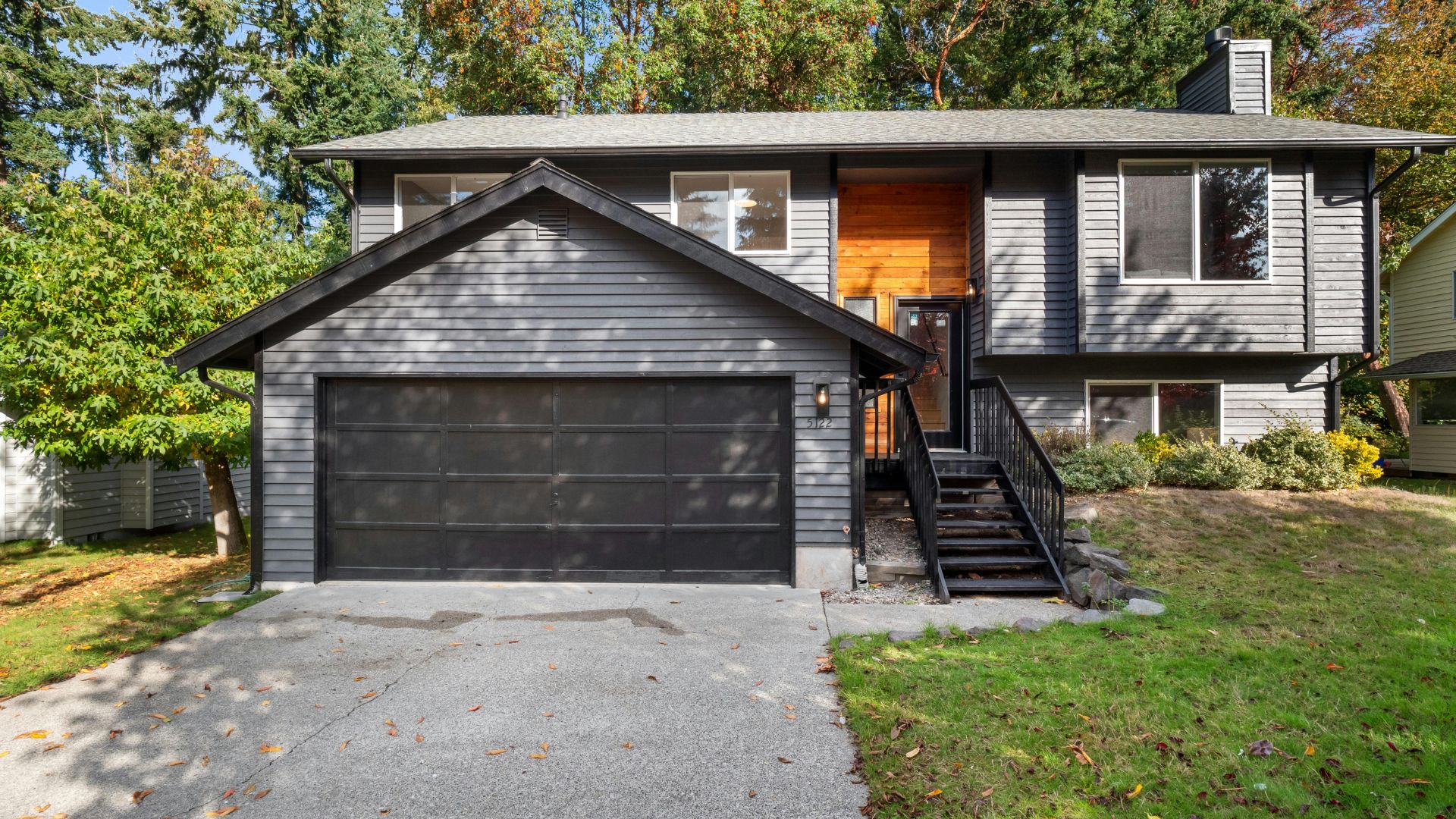 Gray two-story suburban house with black garage and wooden front door