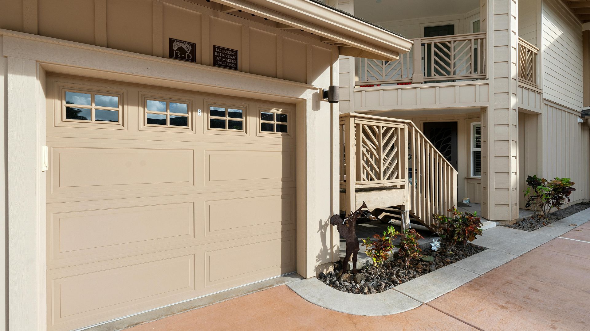 Beige garage with windows, adjacent to wooden stairs and landscaped area