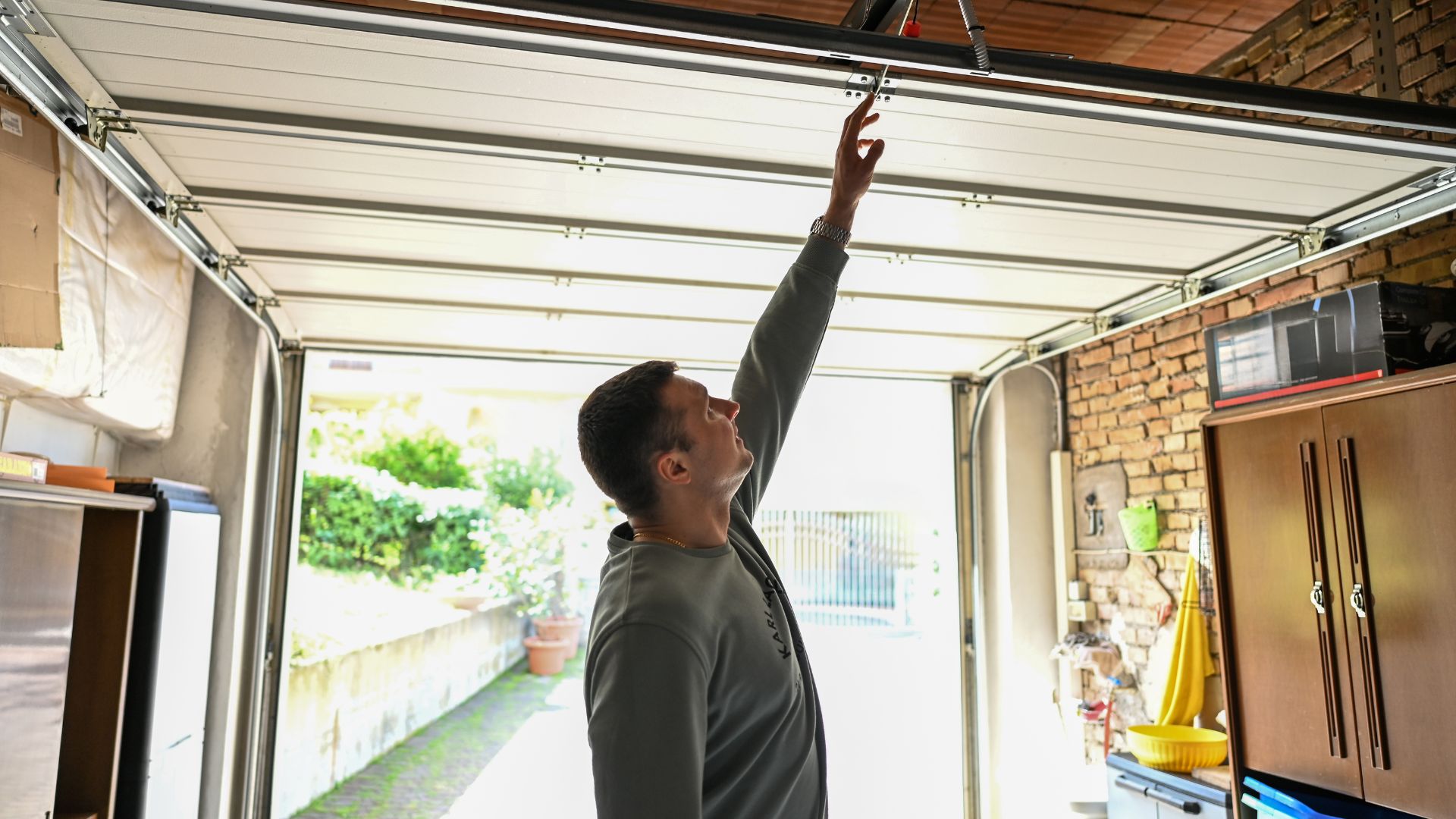 Person operating garage door, reaching up to control mechanism