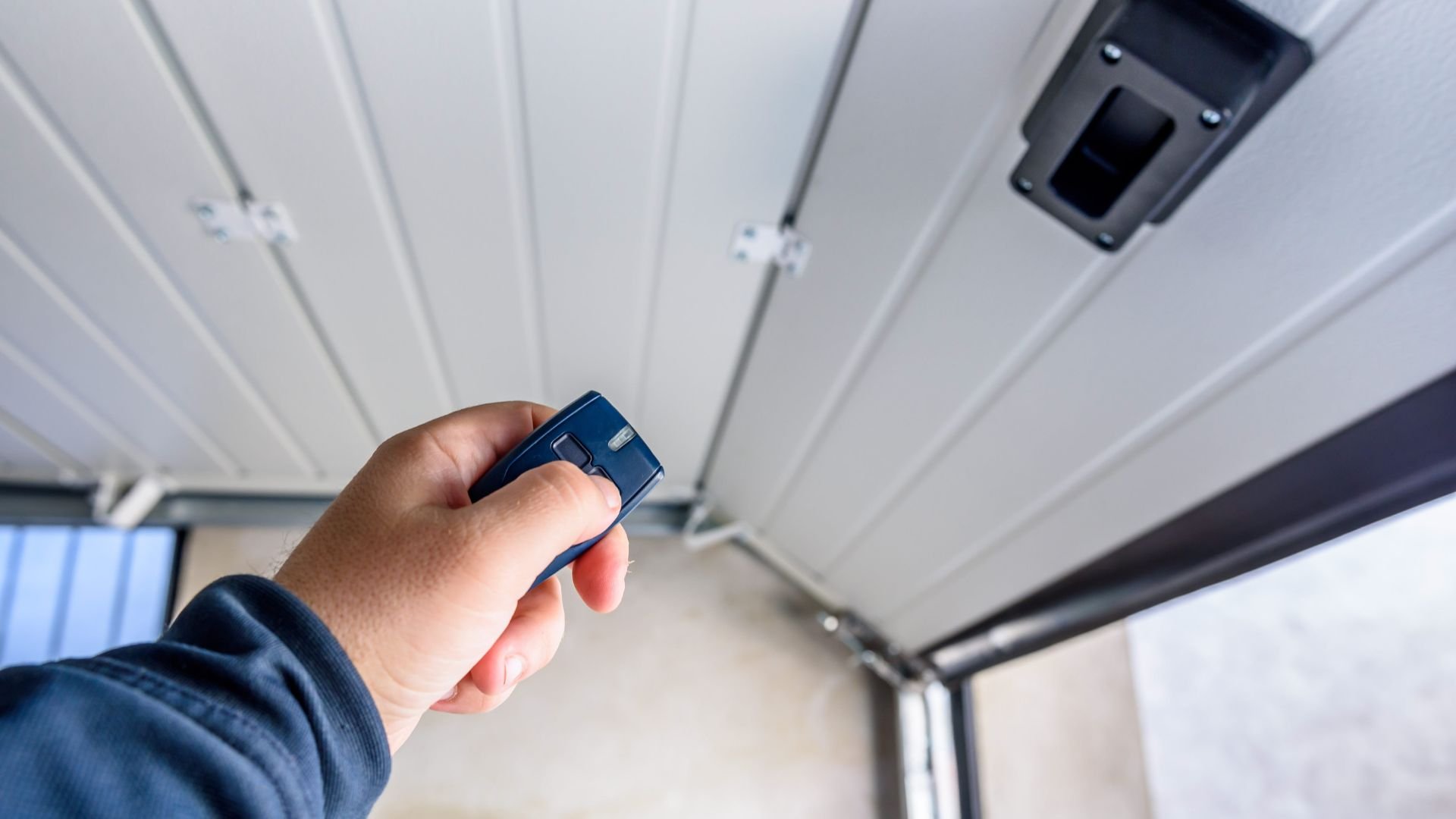 Hand using remote control to operate garage door opener mechanism